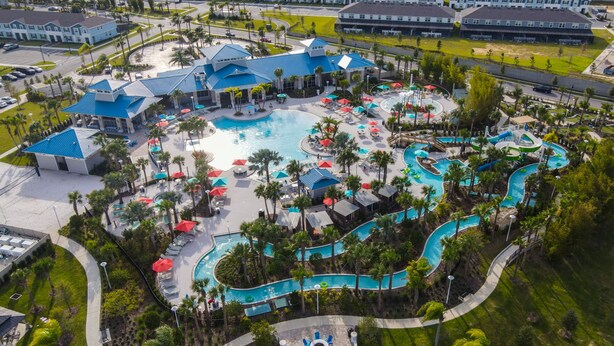 An aerial view of a resort with a central swimming pool, multiple water slides, and a variety of lounge areas.