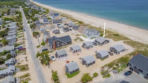 Vue aérienne d’une zone résidentielle côtière, avec des maisons, une plage et une route.