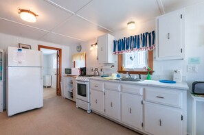 Kitchen with refrigerator, stove, sink, and central island, featuring a tiled backsplash and countertop.