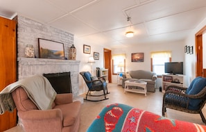 Cozy living room with a brick fireplace, comfortable seating, and a television on a stand.
