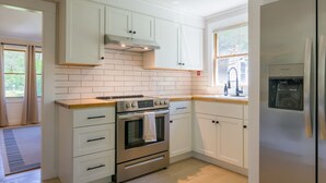 Una cucina moderna con mobili bianchi, un forno in acciaio inossidabile e un dispenser d'acqua integrato.