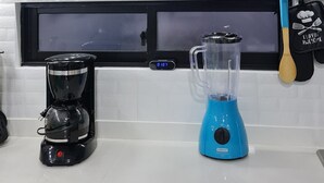 A kitchen with a coffee maker, blender, and pots on the countertop.