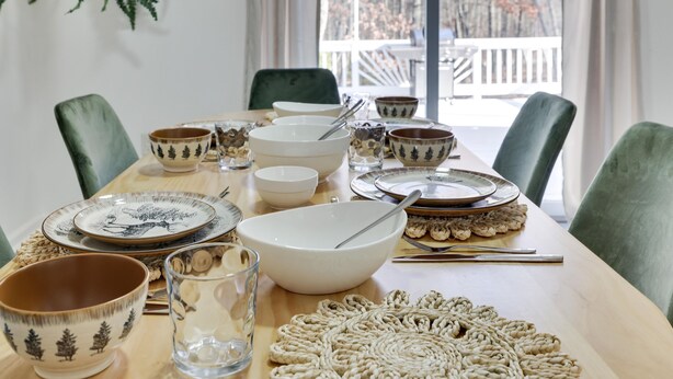Een eettafel gedekt met diverse kommen, borden en bestek.