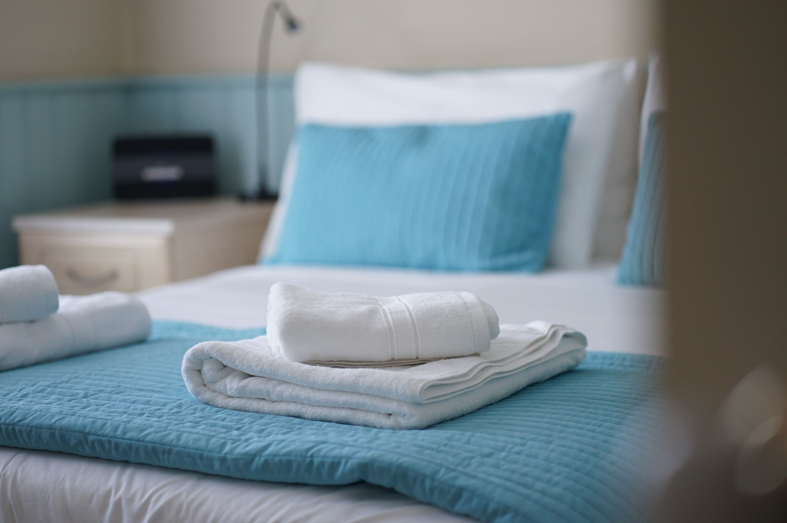 A neatly made bed with blue bedding and white towels.
