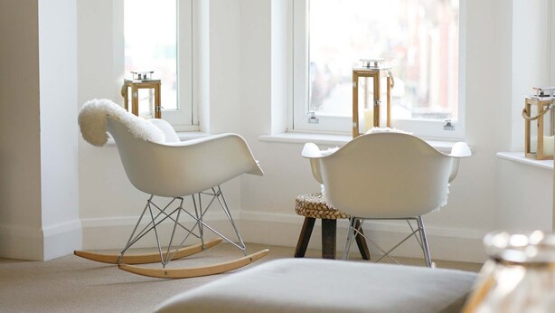 Une pièce avec deux fauteuils à bascule, une petite table et une fenêtre donnant sur un beau paysage.