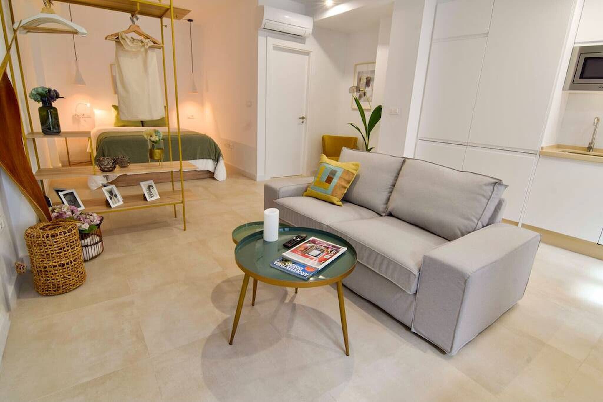 A modern living room with a sofa, a glass coffee table, a hanging chair, and a small side table with a magazine.