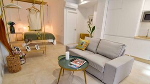 A modern living room with a sofa, a glass coffee table, a hanging chair, and a small side table with a magazine. - Housing Ollerias by Sharing Co (Málaga)
