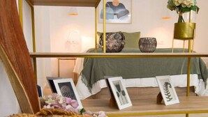 A room with a bed, a shelf with decorative items, and a wicker basket. - Housing Ollerias by Sharing Co (Málaga)