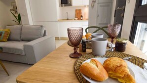 A dining area with a wooden table, a plate of croissants, two glasses, and a bottle of jam. - Housing Ollerias by Sharing Co (Málaga)