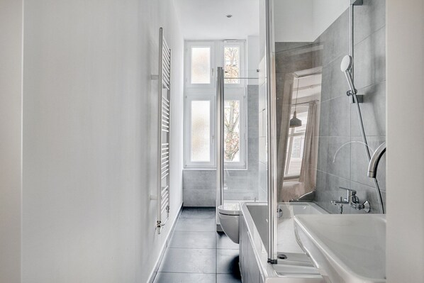 Une salle de bain moderne avec une douche à l’italienne, une baignoire et des toilettes.