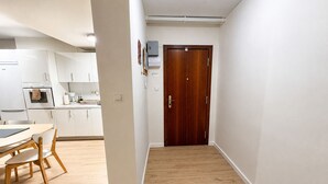 A modern kitchen with white cabinets, a wooden dining table, and a wooden floor.