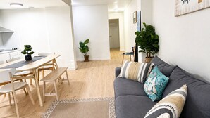 A modern living space with a dining area, a gray sofa with patterned cushions, and a potted plant.