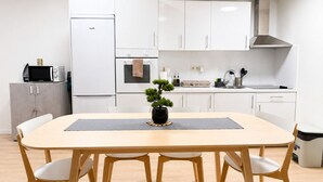 A modern kitchen with white cabinets, a built-in oven, a microwave, and a sink.