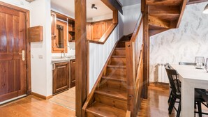A wooden staircase leading to a dining area with a white table and chairs. - Tanau 1700 (Tanau)