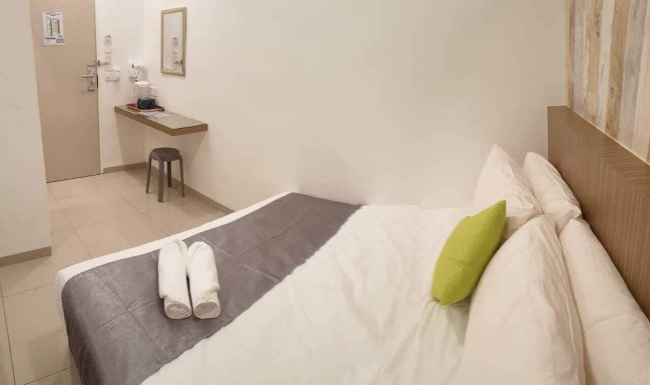 A hotel room with a bed, a desk, and a chair.