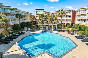 Un hotel con una gran piscina rodeada de palmeras y sillas de descanso.