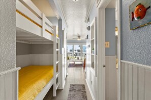 A narrow hallway with bunk beds, a ceiling fan, and a view to an outdoor area. - Great Beach Getaway across from Galveston Babes Beach (Galveston)