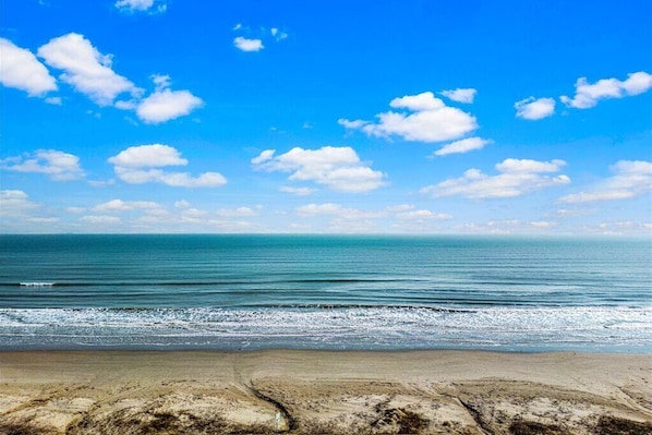 Una playa con cielo despejado y mar tranquilo.