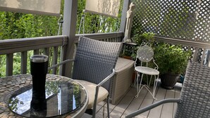 A covered outdoor seating area with wicker furniture, a glass table, and potted plants. - FIRST FLOOR FLAT FOR BUSINESS OR PLEASURE (Buffalo)