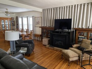 A living room with a fireplace, a television, and a dining area with chairs and a table.