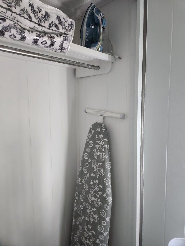 A bathroom with a shower, a towel rack, and an ironing board.