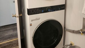 Una lavadora y secadora LG apiladas en una habitación con suelo de madera y paredes blancas.