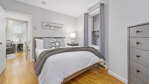 Une chambre à coucher avec un lit, une table de chevet, une lampe et une commode.