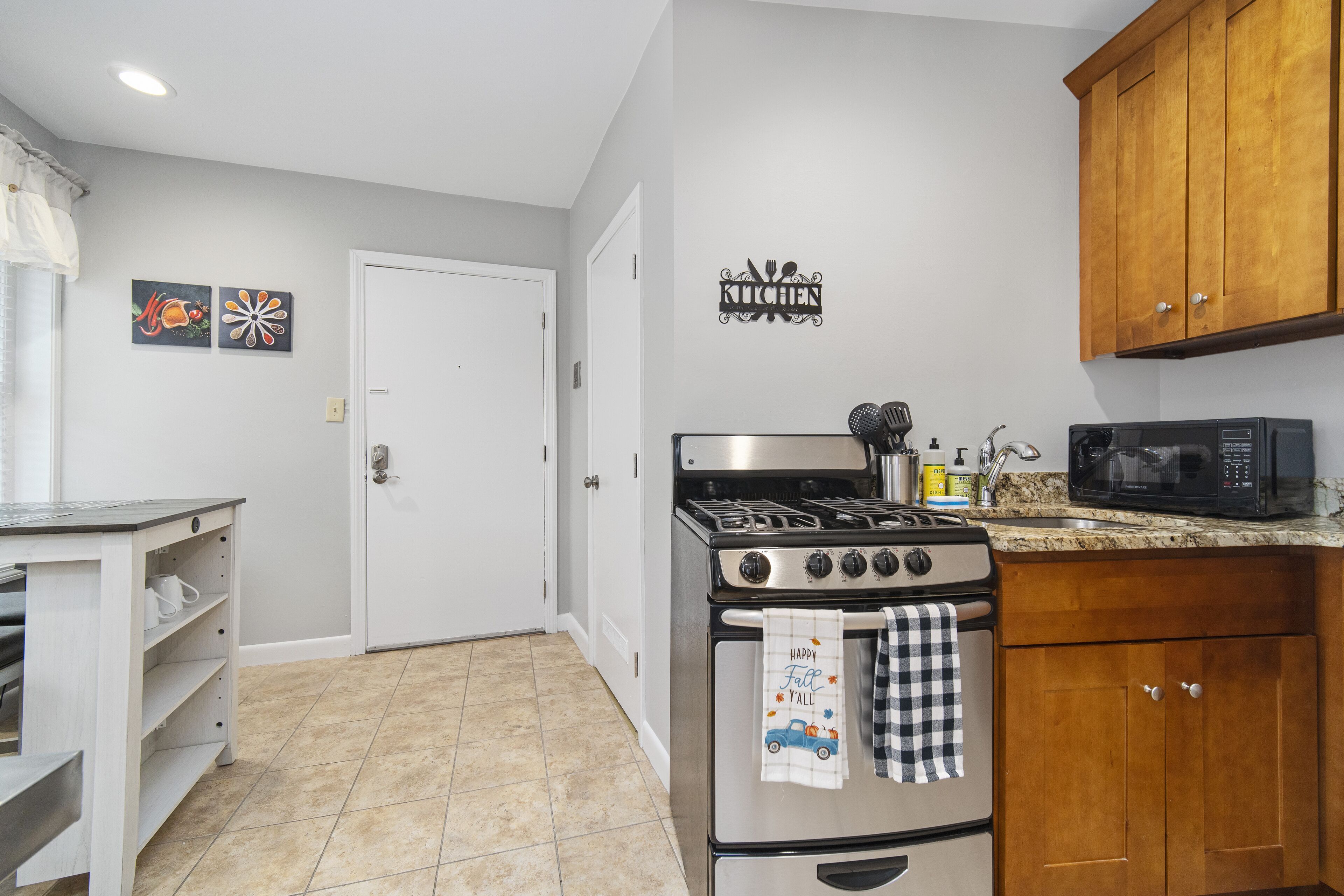 A kitchen with a stove, microwave, and wooden cabinets.