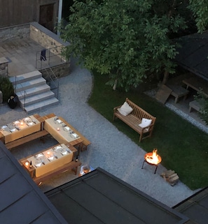 An outdoor patio with tables and chairs, a fire pit, and a wooden bench. - Holiday Apartment "Geigerhaus 500 Jahre - Maisonette" with Mountain View, Shared Terrace & Wi-Fi (Stuhlfelden)