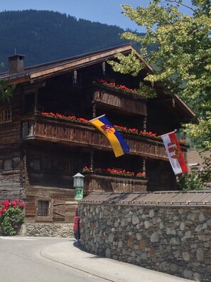 Un chalet en bois doté de balcons, de murs en pierre et de drapeaux.