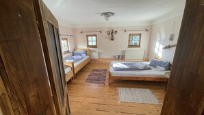 Un dormitorio con suelo de madera, dos camas, un radiador y una ventana.
