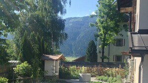 Un patio con un sendero de grava, un pequeño jardín y vistas a la montaña.