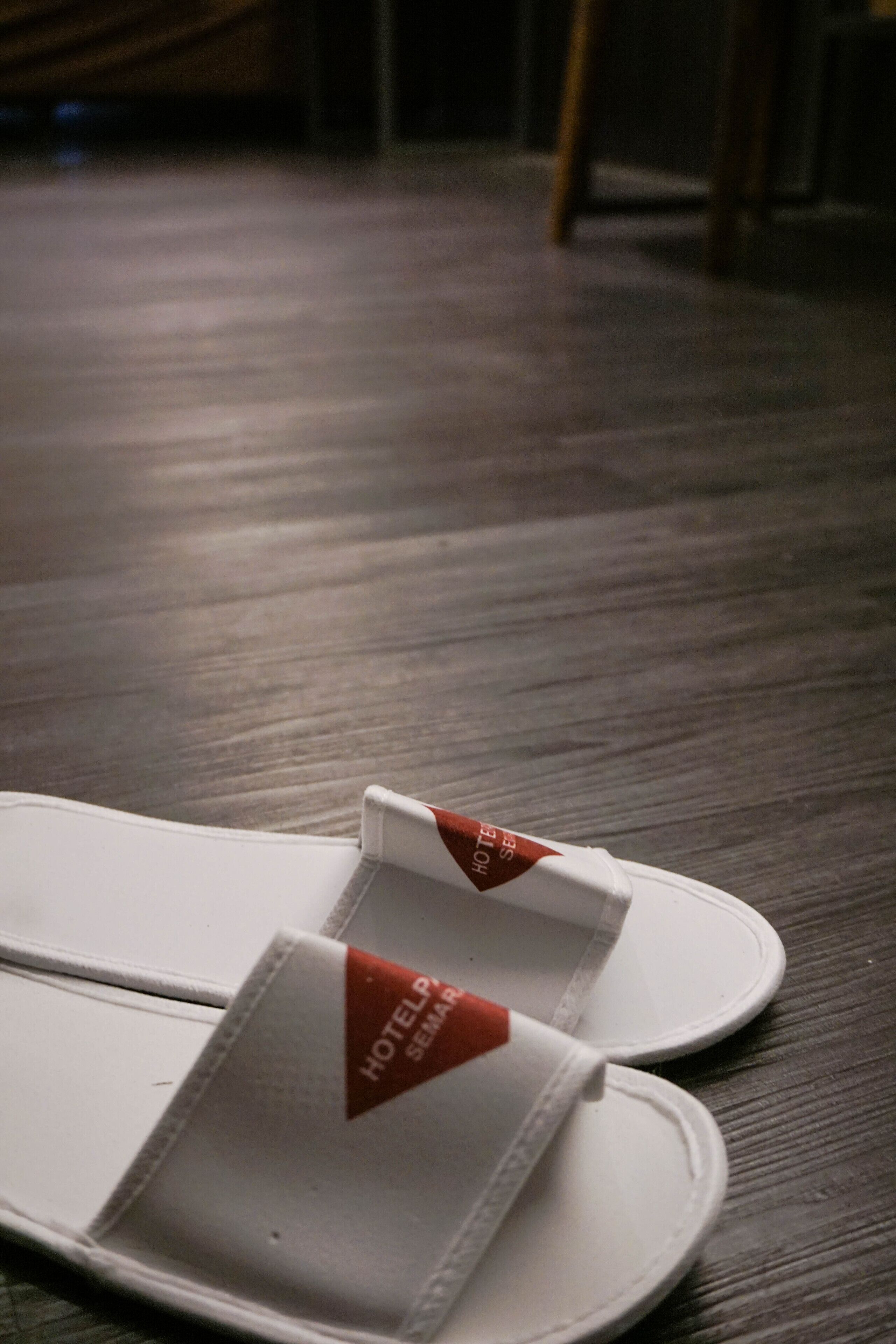 A pair of white slippers with a red tag labeled "HOTEL SEMANA".