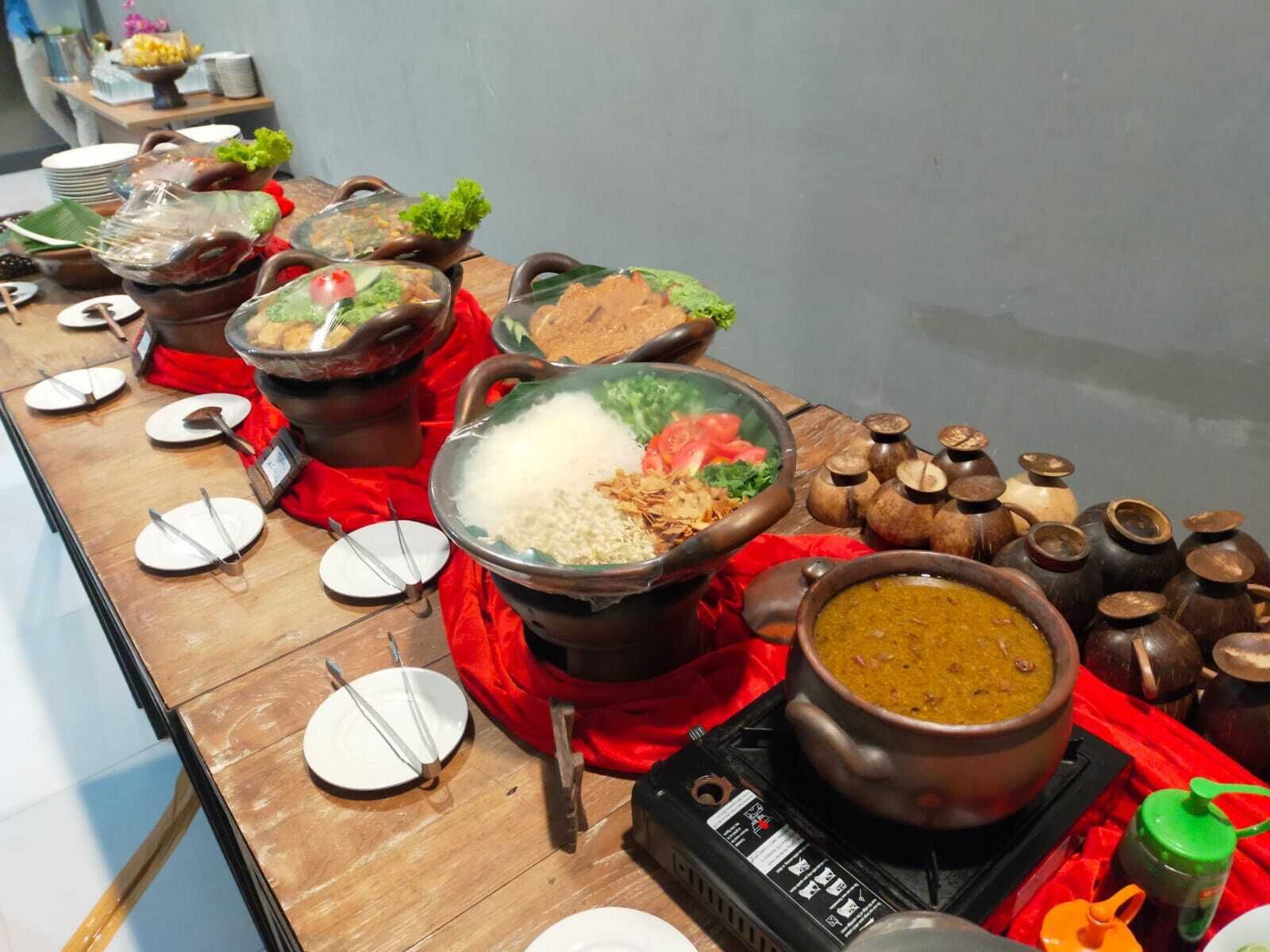 Una mesa de buffet con diversos platos, como arroz, verduras y una olla de sopa.
