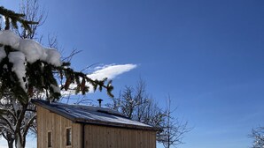 Une cabane en bois avec un toit en pente, entourée d’un paysage enneigé et d’arbres.