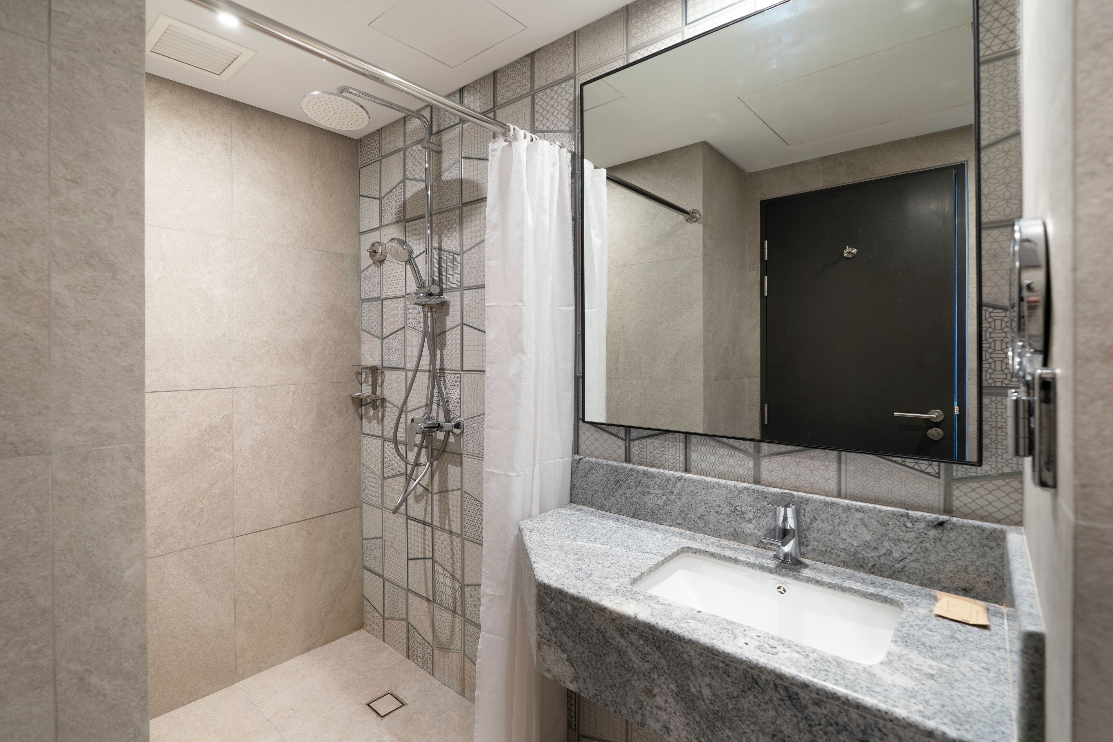 A modern bathroom with a shower, a sink, and a large mirror.