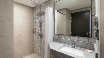 A modern bathroom with a shower, a sink, and a large mirror.