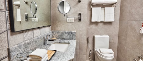 Un baño moderno con lavamanos de granito, un espejo, un inodoro y un perchero para toallas.