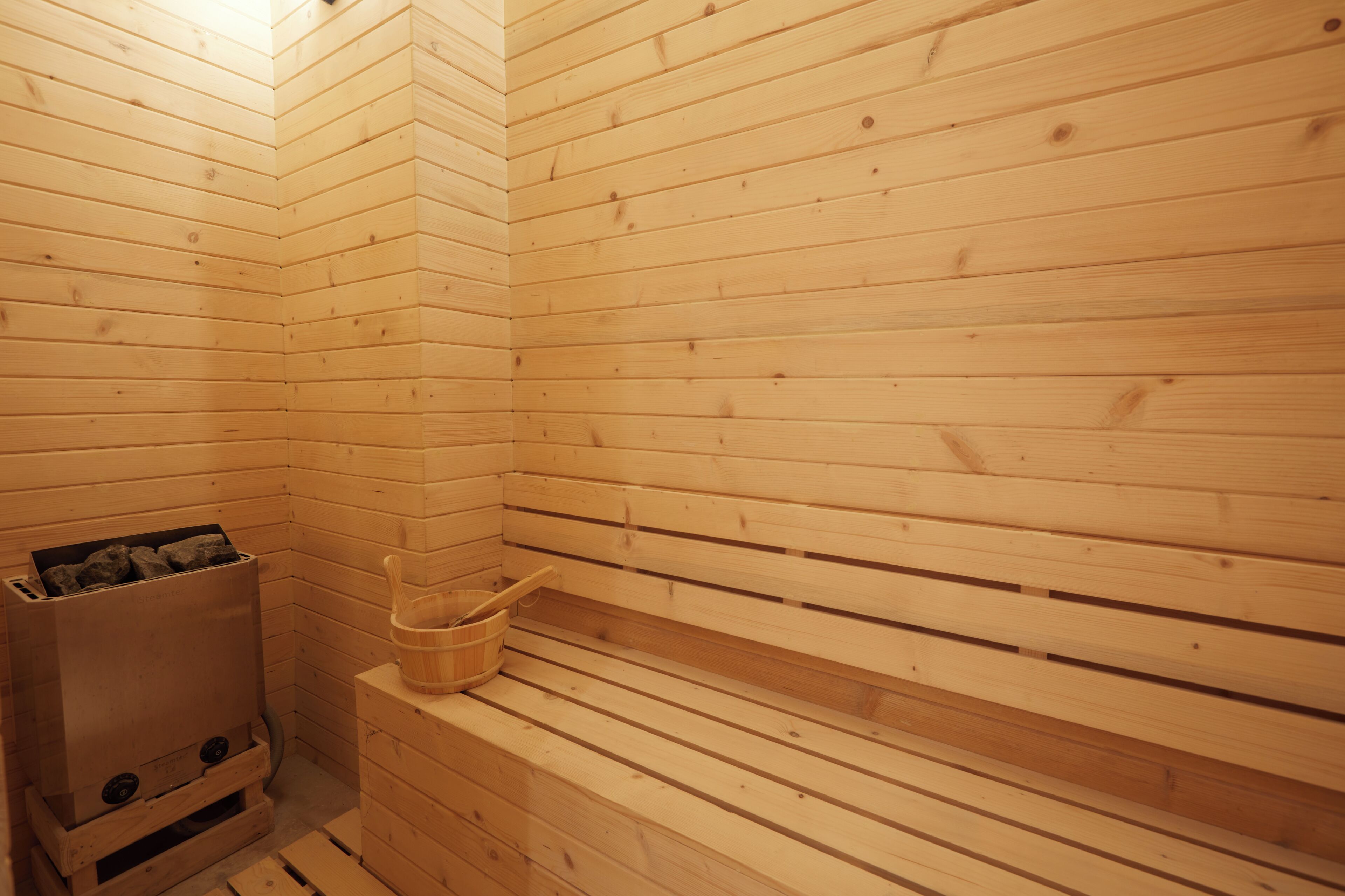 A wooden sauna with benches and a stone heater.