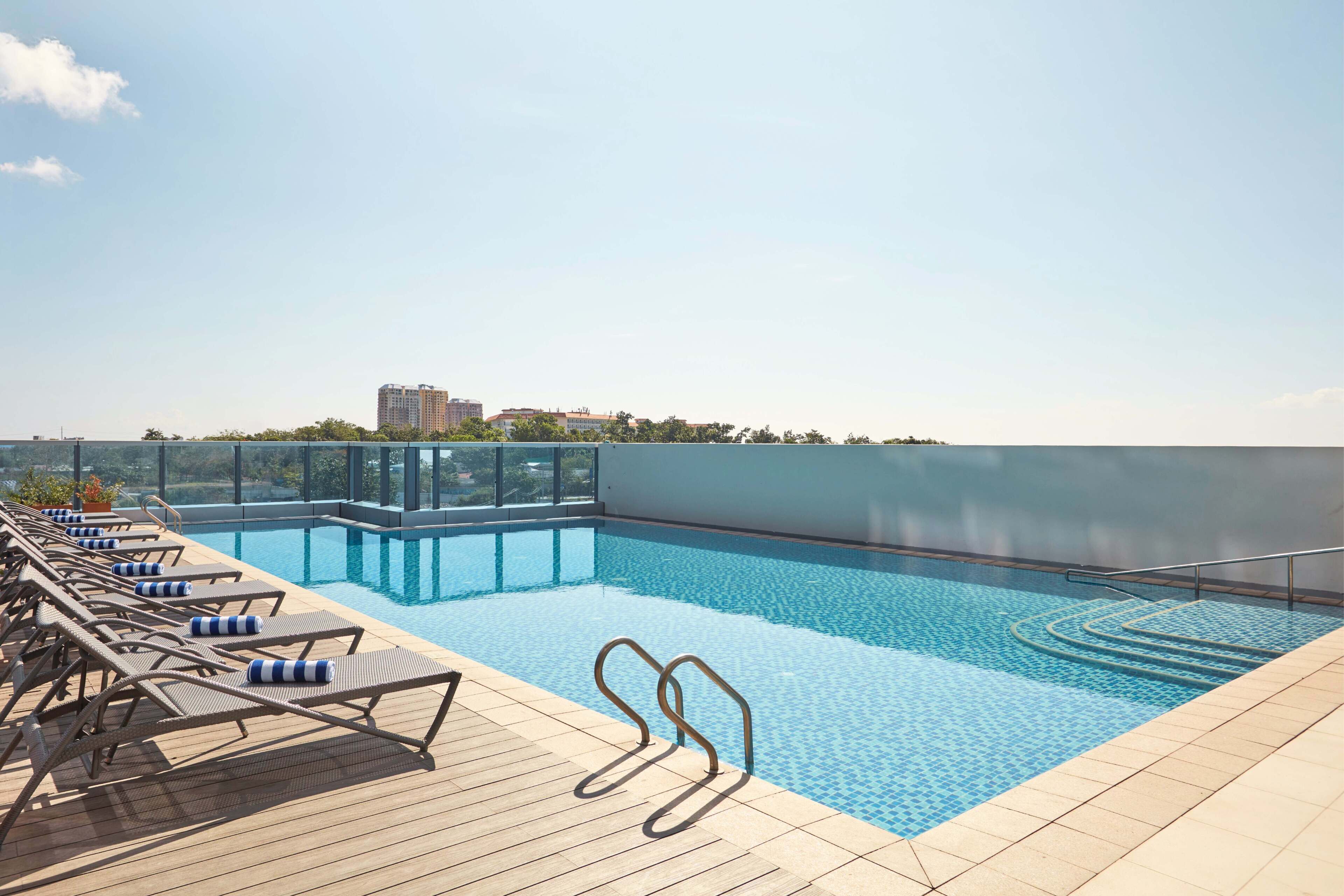 A rooftop swimming pool with lounge chairs and a glass railing.