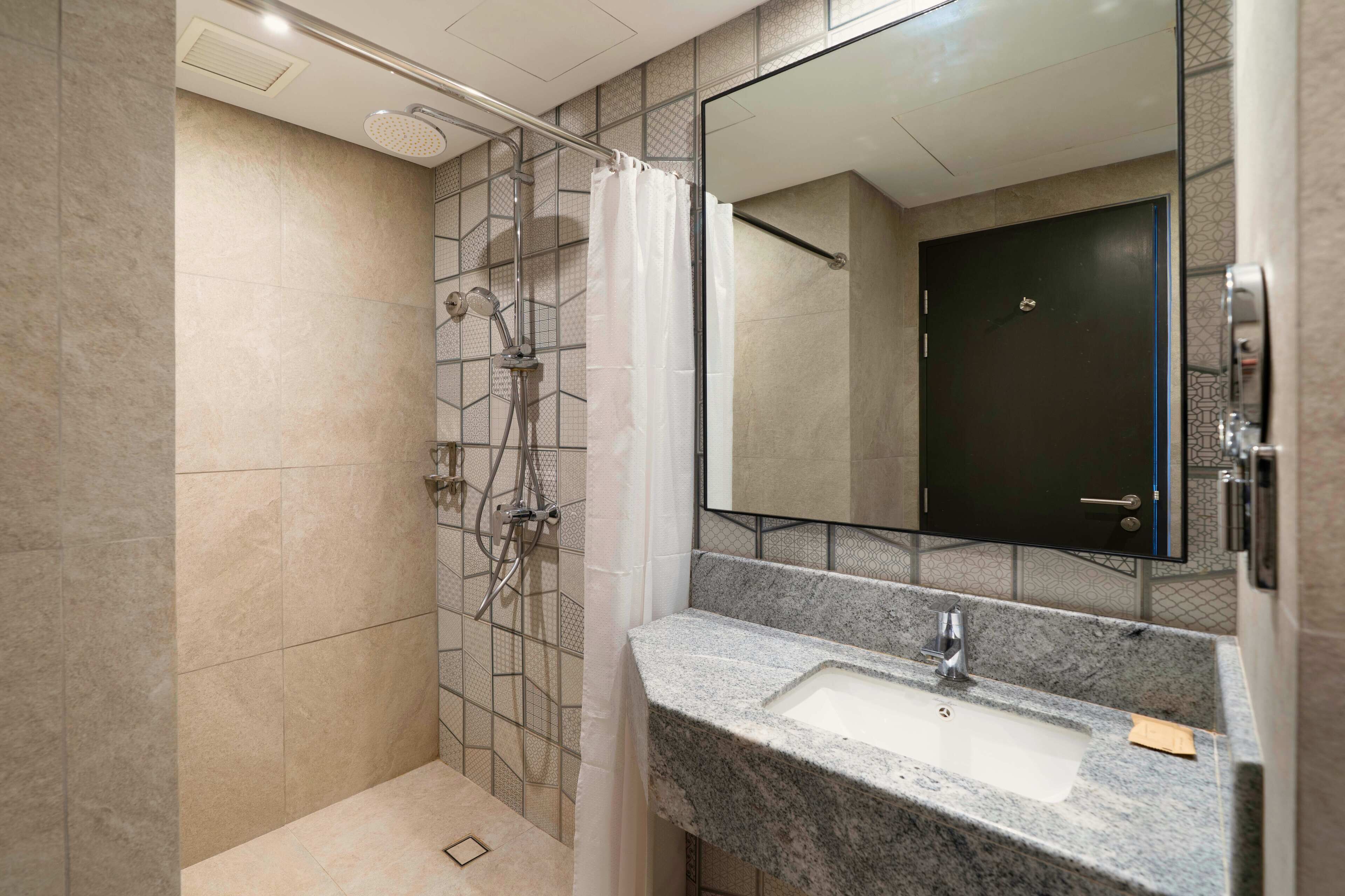 A modern bathroom with a shower, a sink, and a mirror.