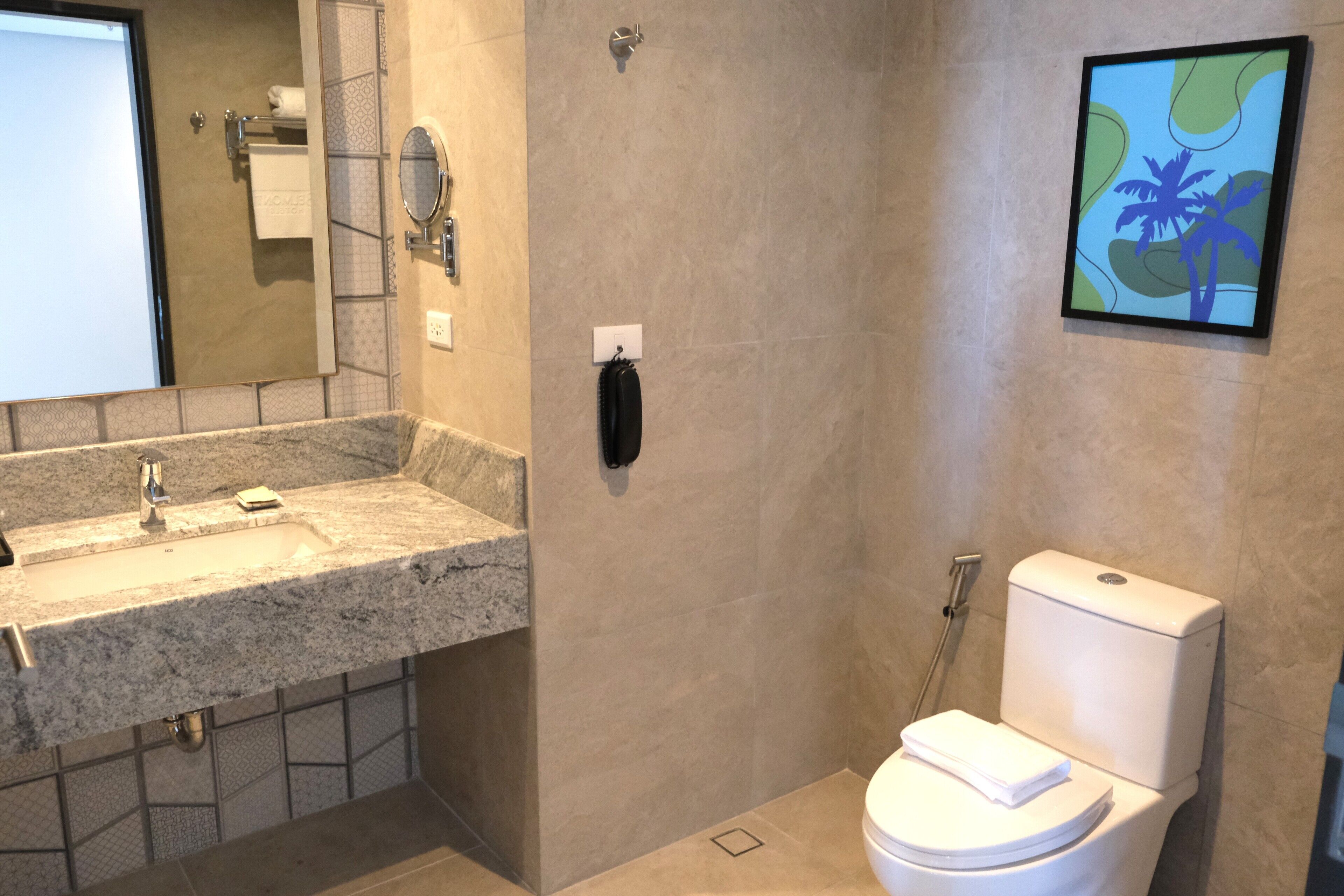 A bathroom with a granite sink, a toilet, and a shower.