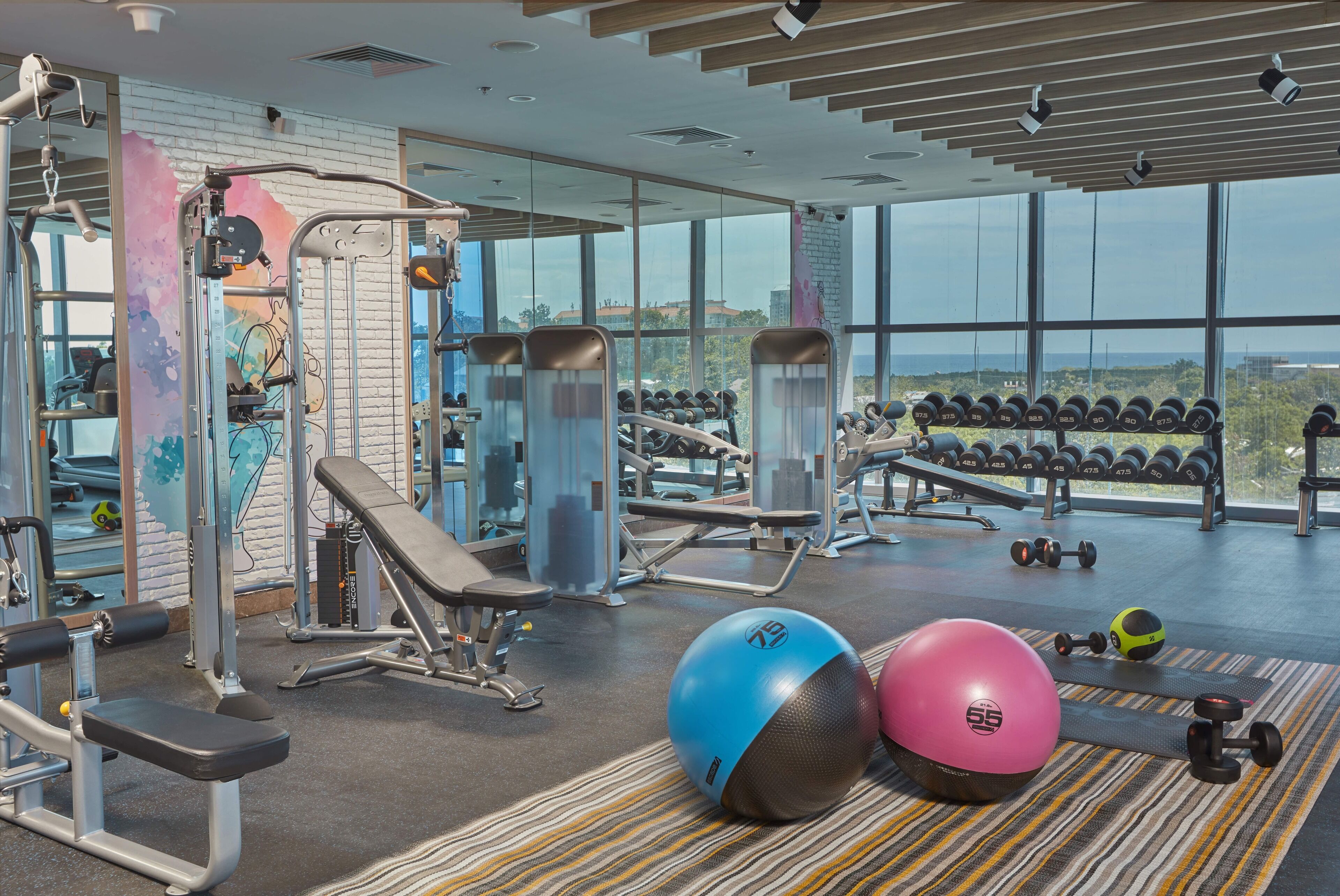 A gym with various exercise equipment, weight racks, and exercise balls.