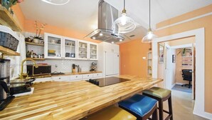 Une cuisine moderne dotée d’un îlot central en bois, de meubles blancs et d’une hotte de cuisine en acier inoxydable.