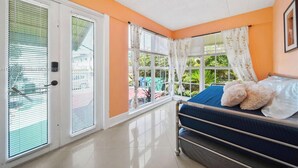 Une chambre avec un lit, une fenêtre avec des rideaux et une vue sur la verdure.