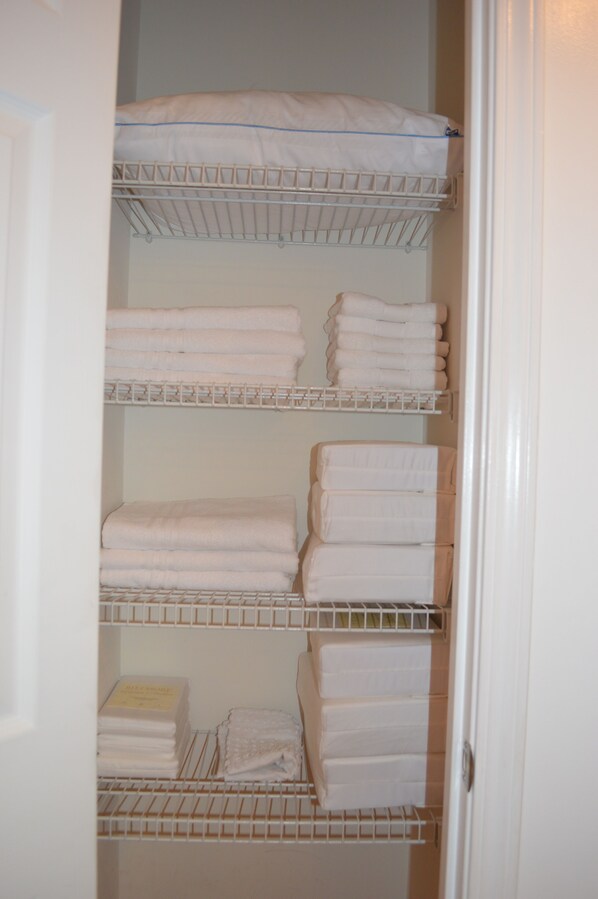 A storage closet with multiple shelves holding folded towels and linens.
