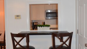 A compact kitchen with a central island, two bar stools, a microwave, and a coffee maker.