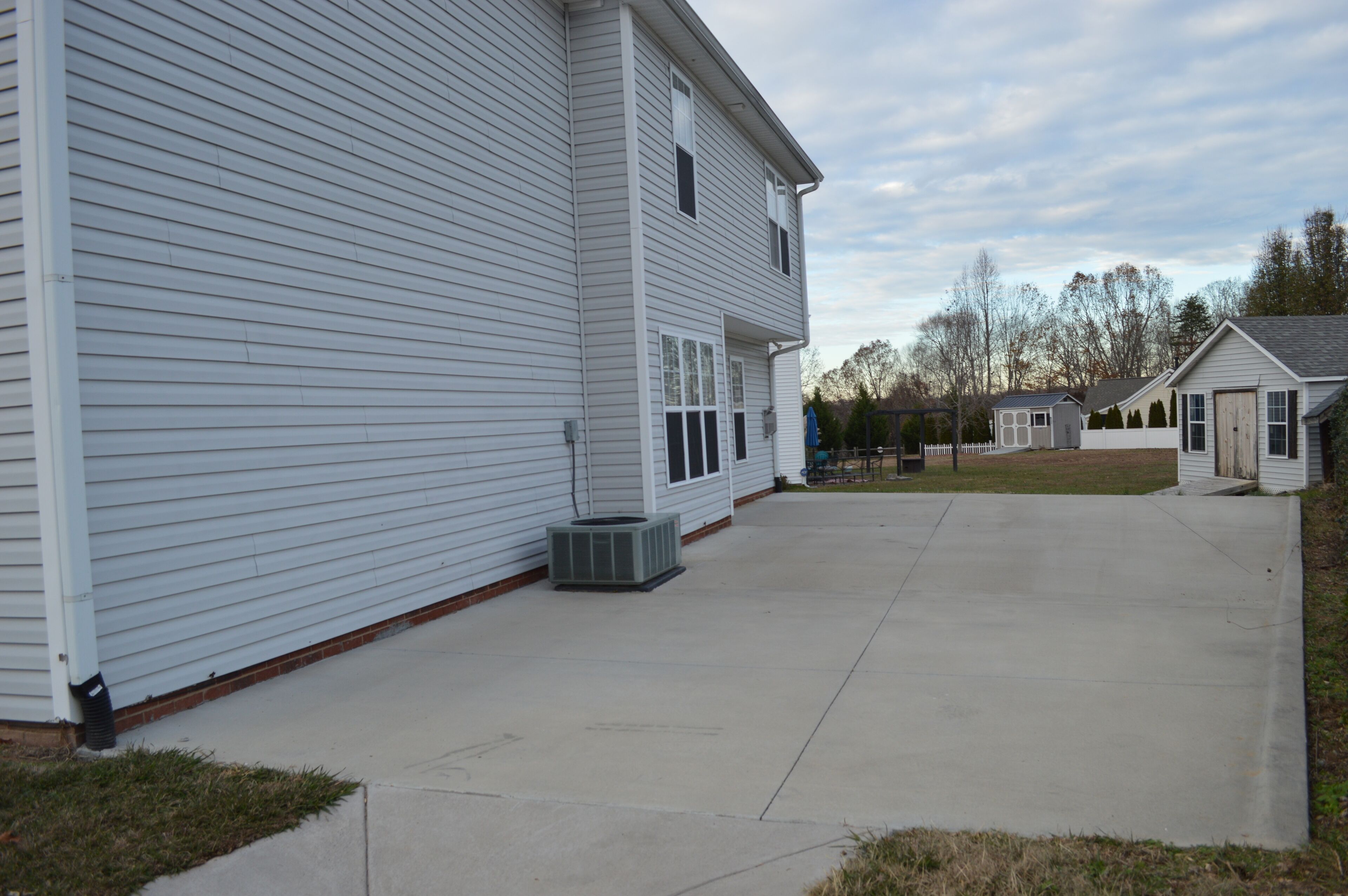 A two-story house with a covered patio area and a small shed.