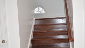 A wooden staircase with white walls and a door on the left.