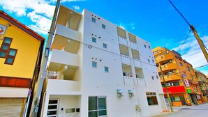 Un edificio de varios pisos con fachada blanca, varios balcones y una entrada a nivel de calle.